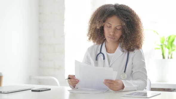 Afrcian Doctor Reading Documents while Sitting in Clinic