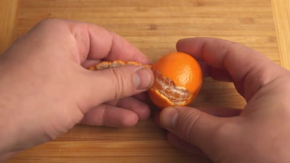 A Man Peels a Tangerine