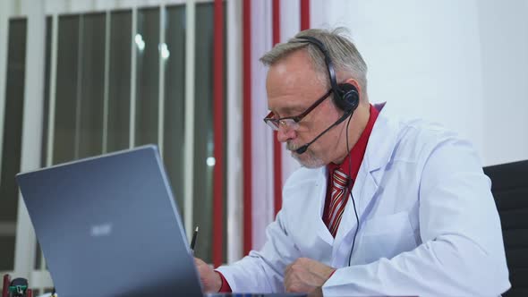 Man Having Video Call With Patient. Doctor with headset gives online consultation using laptop