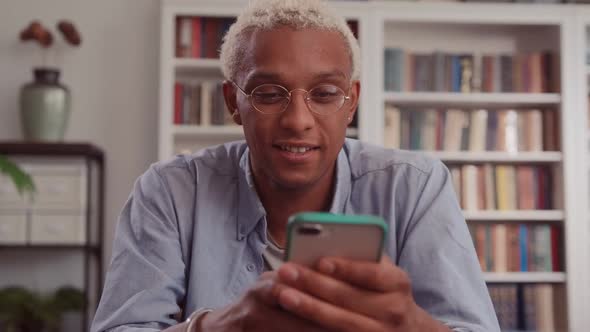 Portrait of Handsome and Successful African Man Uses Smartphone at Home Office