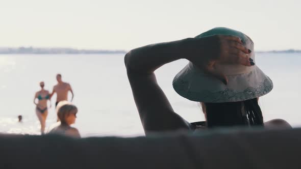 Relax on the Beach. View From the Back on Woman in a Hat Lying on the Shore