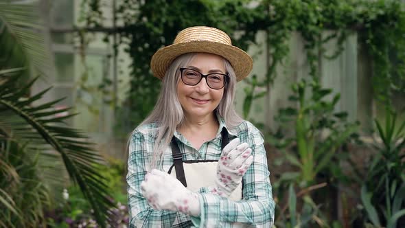 Elderly Woman with Long Grey Hair in Straw Hat and Workwear Which Posing