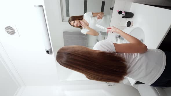 Cute Woman Combing Beautiful Long Hair in Bathroom