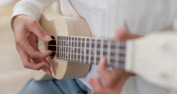 Woman play ukulele at home