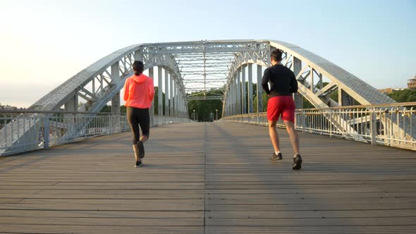 A couple running across a bridge