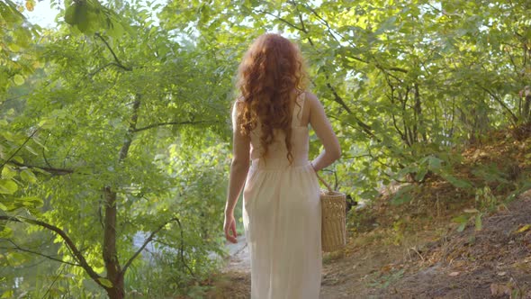 Back View of a Young Nice Woman Dressed in Light White Clothes Walking in the Autumn Forest with a