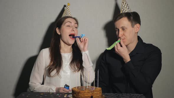 Young Couple Celebrates a Holiday He Sits Alone at a Table with a Cake and a Candles