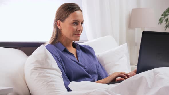 Young Woman with Laptop in Bed at Home Bedroom