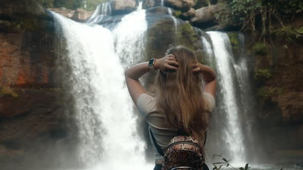 Sensual Woman is Enjoying Nature on Waterfall in Jungles Touches Her Long Hair