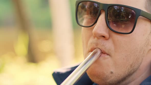 A Handsome Young Man in Sunglasses Smokes a Hookah