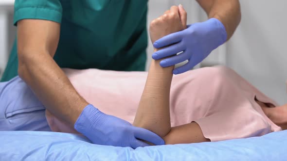 Traumatologist Moving Female Patient Arm, Rehabilitation After Joint Trauma