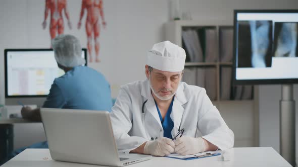 Portrait of Overworked Doctor Sitting in His Office