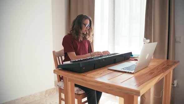 Young Woman Learning Piano with an Online Course Using Her Laptop