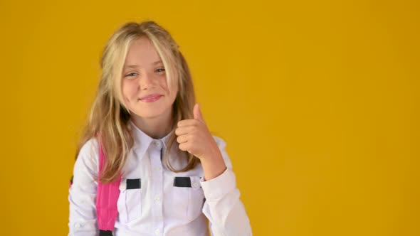 Happy smiling blonde teenager girl jumping into the frame shows thumbs up