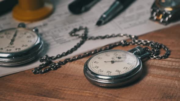 Antique Stopwatch Lies on Wooden Desk with Old Documents and Counts Seconds