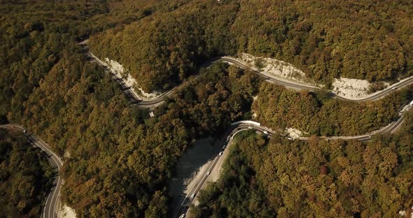 Aerial View of Car Driving Along The Winding Mountain Pass Road Through The Forest Trees. Autumn