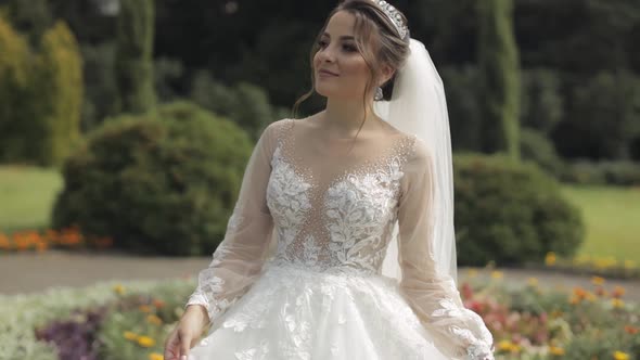 Beautiful and Lovely Bride in Wedding Dress and Veil in the Park Waiting for Groom. Slow Motion