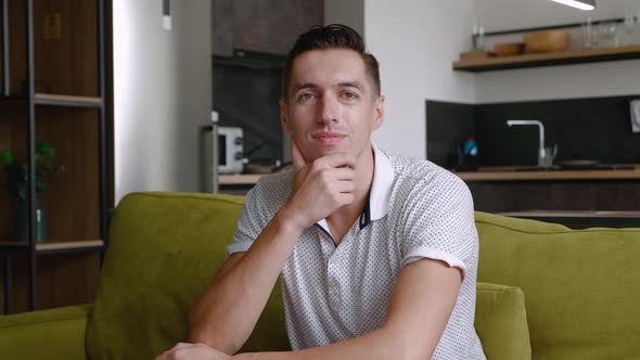 Portrait of Happy Man Is Resting While Sitting on Couch at Home. A Young Male Enjoys the Lifestyle