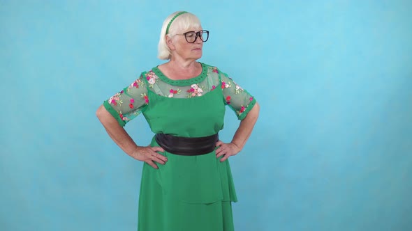 Confused Elderly Woman with Glasses Stands on a Blue Background