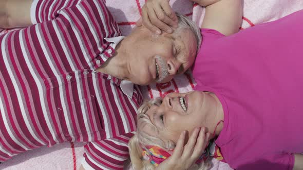 Family Weekend Picnic. Active Senior Old Caucasian Couple Lie on Blanket Facing Each Other and Talk