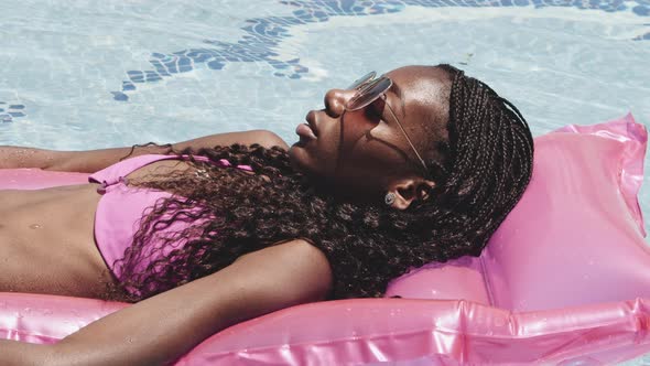 Lady in Pink Bikini and Lying on Pink Inflatable By the Pool