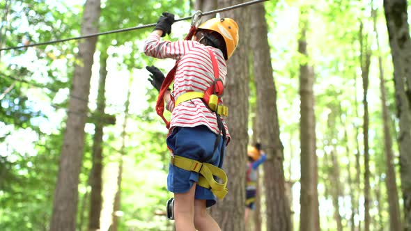 Boy Walking on a Tightrope Holding His Hands on a Safety Rope