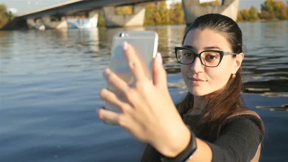 Pretty Girl Takes Pictures of Herself Against the Background of the River