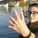 Pretty Girl Takes Pictures of Herself Against the Background of the River - VideoHive Item for Sale