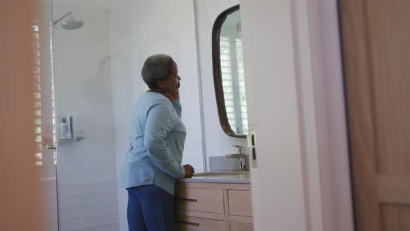 African american senior woman looking at mirror in bathroom