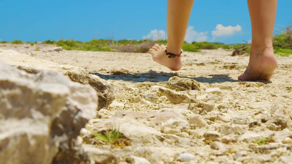 Curacao - A girl walking barefoot on an off-road adventure on a sunny day - Wide shot