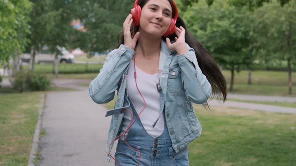 Beautiful Cheerful Girl Dancing Walking in the Park with Headphones