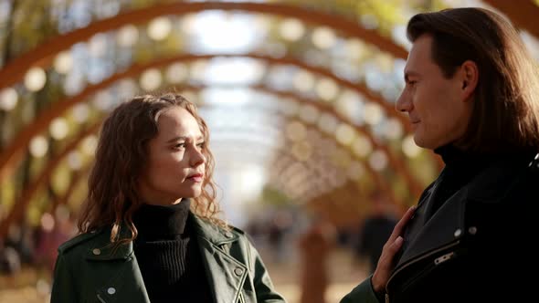 Portrait of a Blonde and a Man Against the Background of Blurred Arches on a Sunny Day