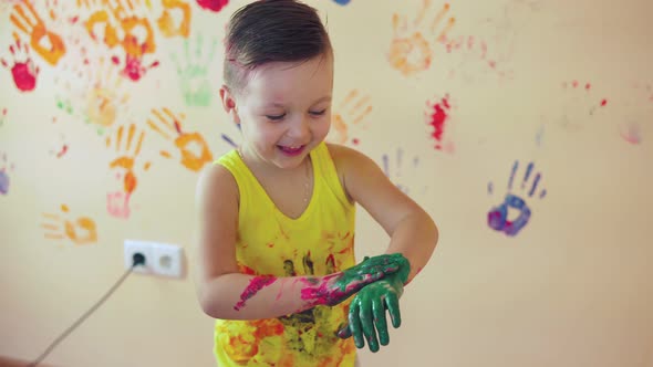 Close Up Veiw of Cute Little Boy with Painted Hands After Leaving His Colorful Handprints on the