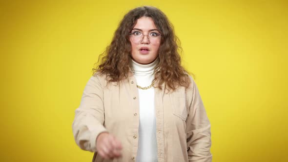 Portrait of Young Woman in Eyeglasses Pointing at Camera Making Shocked Facial Expression