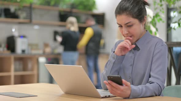 Indian Woman with Laptop Using Smartphone at Work