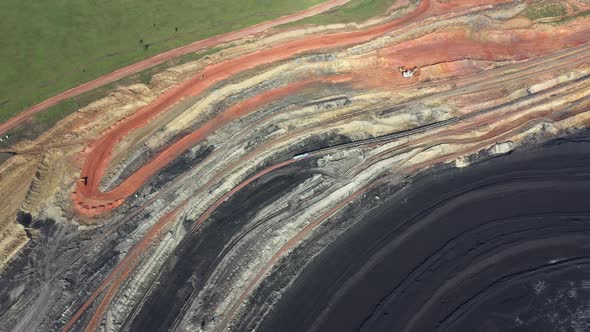 Aerial view. A freight train rides through a coal mine and the camera makes a turn. 