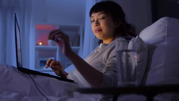 Woman with Laptop in Bed at Home at Night