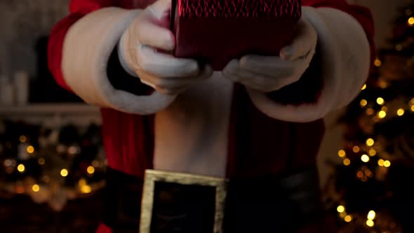 Close Up Hand Santa Claus Gives Gift in Festive Red Box Christmas Holidays