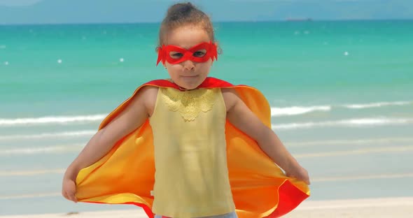 Beautiful Little Girl in the Superhero Costume, Dressed in a Red Cloak and the Mask of the Hero