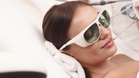 Close-up of Beautician Using Neodymium Laser on Woman Face in Protection Glasses