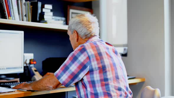 Senior man using desktop computer at home 4k