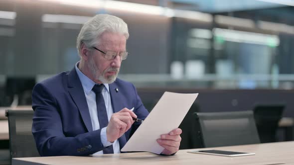 Old Businessman Celebrating Success on Documents in Office