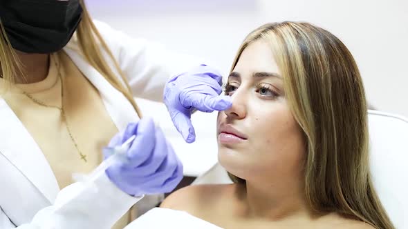 Crop anonymous beautician injecting botox in female face