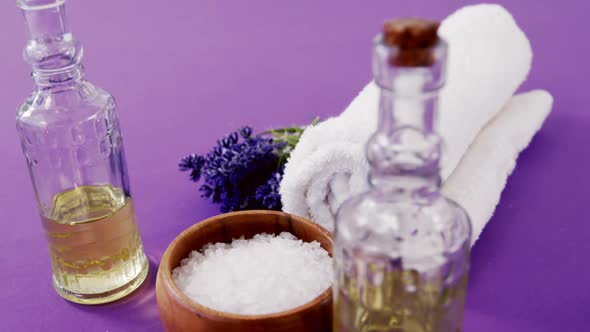 Sea salt in wooden bowl, towel, oil, candle and flowers