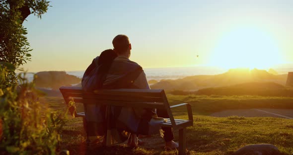 Rear view of couple sitting on bench near beach 4k