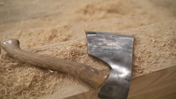 A Sharp Ax Lies on a Wooden Bar and Sawdust