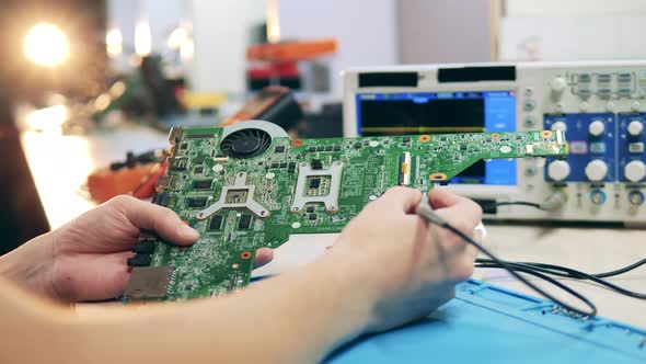 Repairman Checking Motherboard Using Oscilloscope