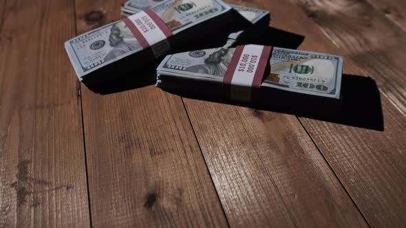 Three Stacks of 10000 American Dollars Banknotes in Bundles Lie on Wooden Table