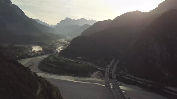 Aerial view of freeway interstate road in italian alps with fast moving traffic and rural green