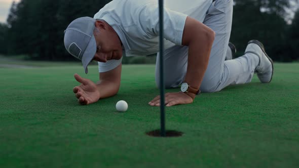 Professional Golf Player Inspect Golfing Ball Hole on Green Grass Course Field